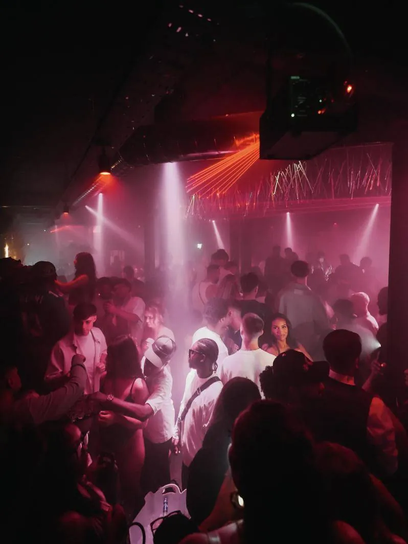 A packed dancefloor in pink light and lasers