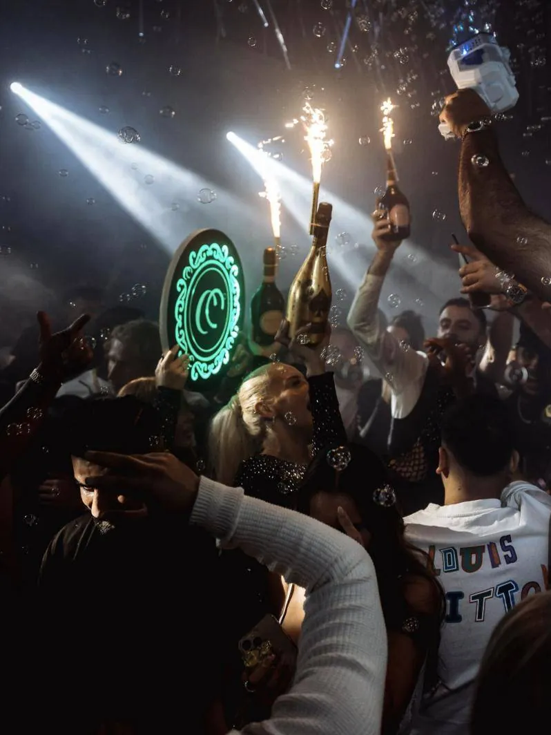 Sparkler bottles and the lit crest under spotlights and bubbles